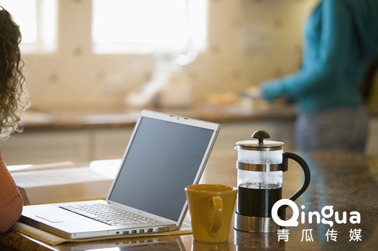 Young woman drinking coffee and working on her laptop in the morning